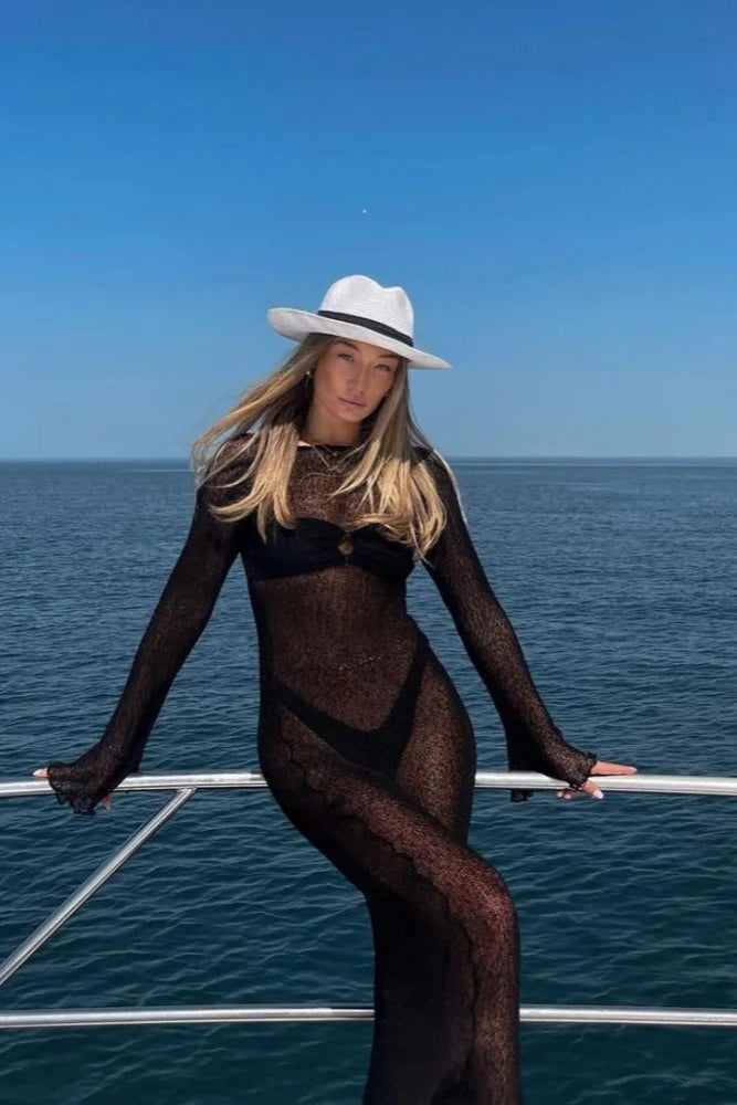 Woman in black swimsuit and sheer cover-up standing in a cruse