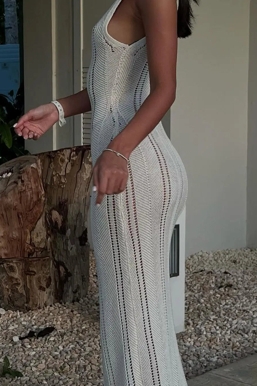 Woman wearing a light white sleeveless dress standing outdoors.