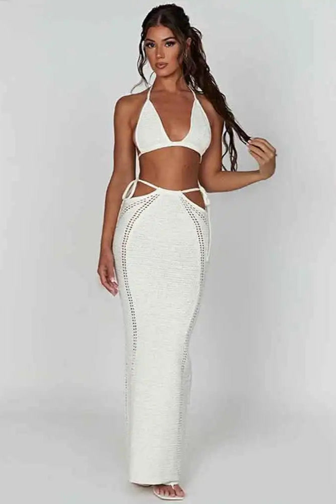 Woman wearing a white bikini with a long white skirt on a plain background