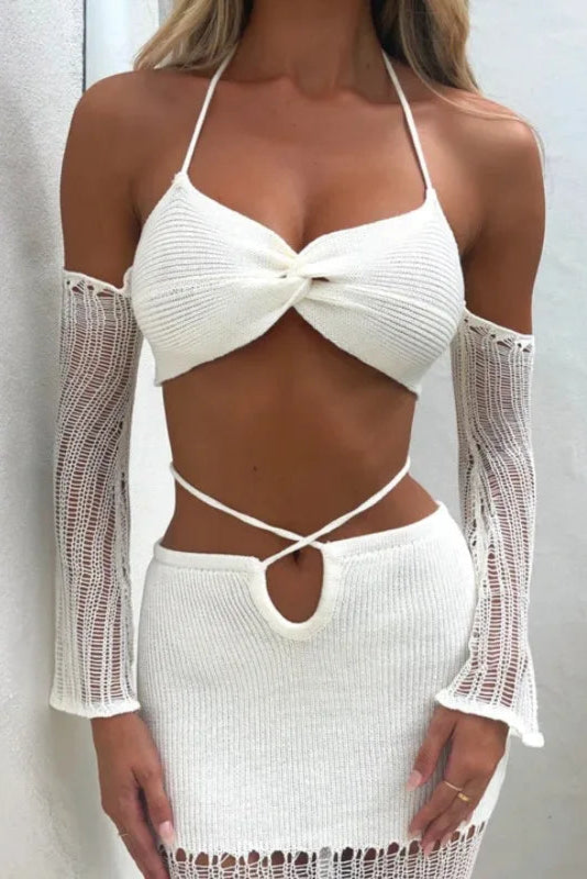 Woman wearing a white crochet outfit with long sleeves against a light background