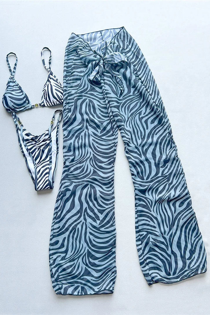 A 3-piece swimwear set laid flat on a light gray background, featuring matching high-waisted wide-leg pants and a triangle bikini. The fabric has a blue and white zebra print pattern.