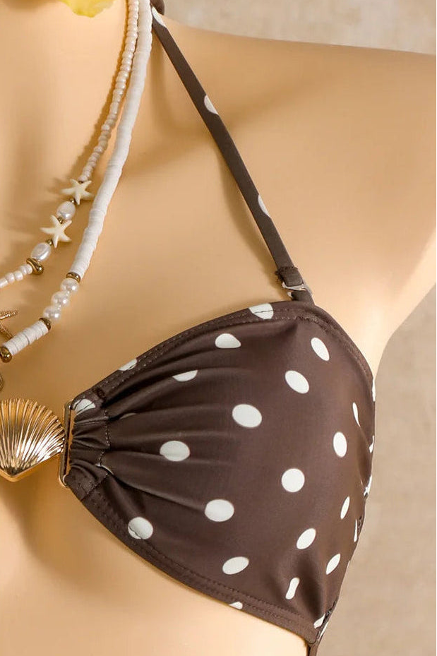 A close-up of a brown halter bikini top with white polka dots