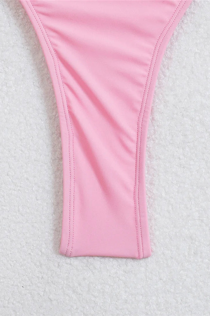 A close-up of a pink bikini bottom thong-style swimwear