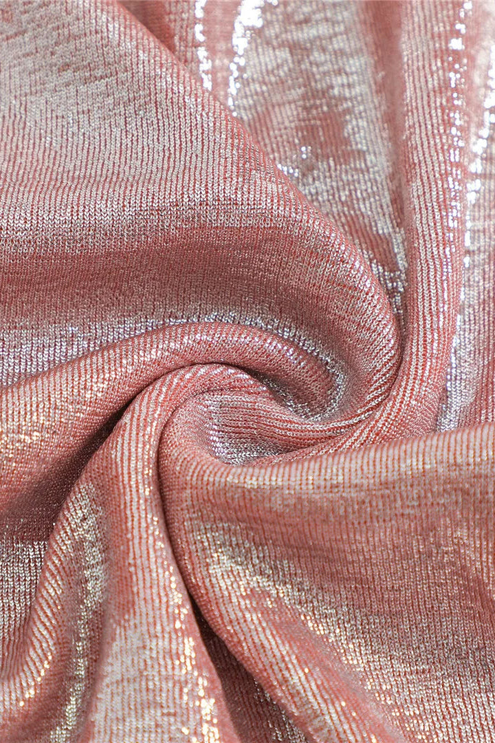 A close-up of shimmering metallic fabric in a dusty rose pink color with reflective silver highlights, arranged in a spiral drape to show texture and sheen.