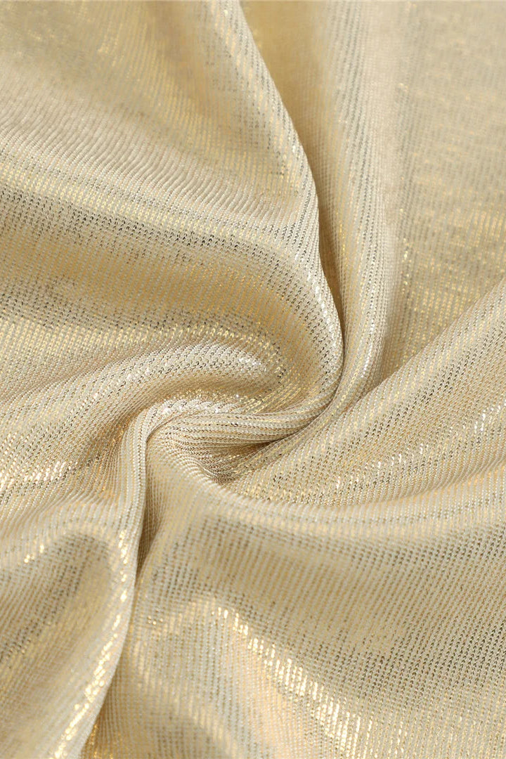 A close-up of shimmering metallic fabric with a soft gold sheen, shown gathered in folds to highlight its texture and reflective quality.