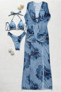 A coordinated swimwear set laid flat on a light textured background, including a long blue floral cover-up, a matching bikini top, bikini bottom