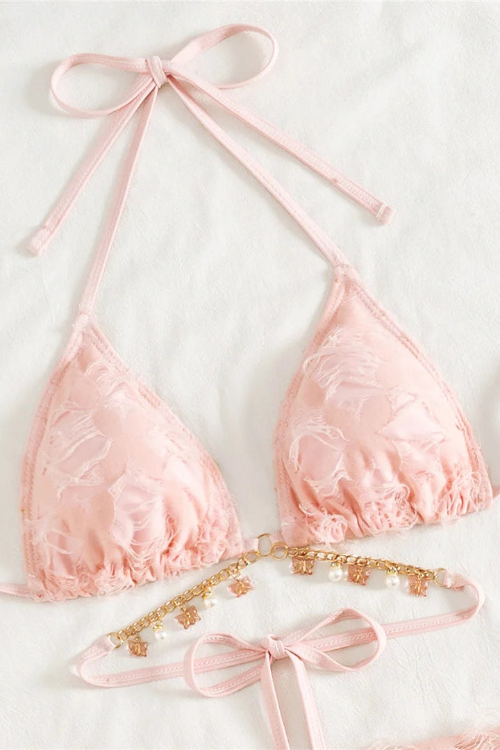 A light pink lace triangle bikini top with matching tie straps and a decorative gold chain with pearl accents.