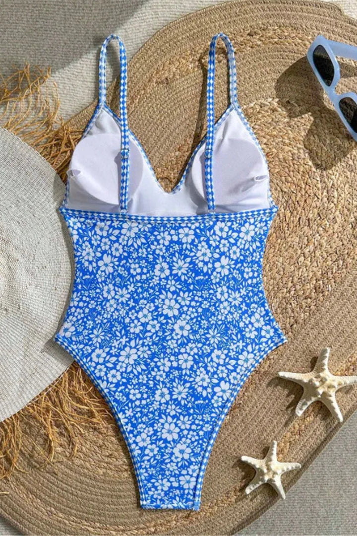 A one-piece bikini swimsuit with blue-and-white patterned straps and a blue-and-white floral print body. 