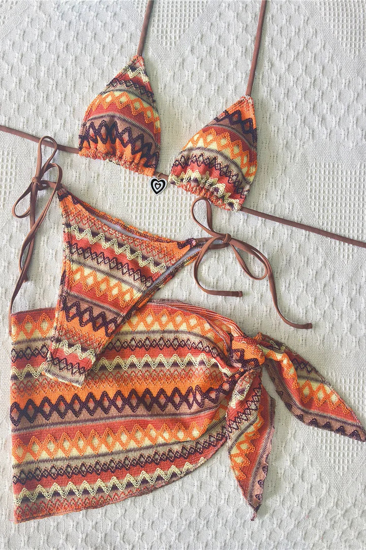 A two-piece bikini set with a matching tie-front sarong, featuring a vibrant orange, brown, and beige geometric pattern