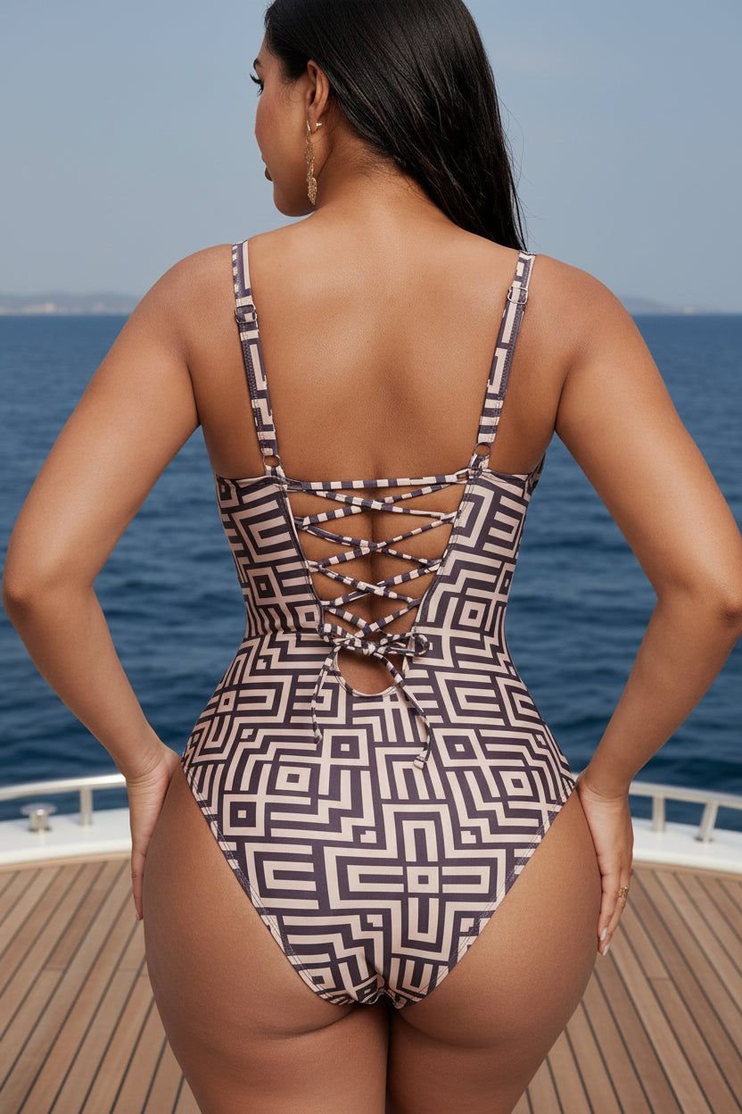 A woman shown from the back wearing a one-piece swimsuit with a geometric pattern. Lace-up detailing adds a fashionable touch to the swimsuit