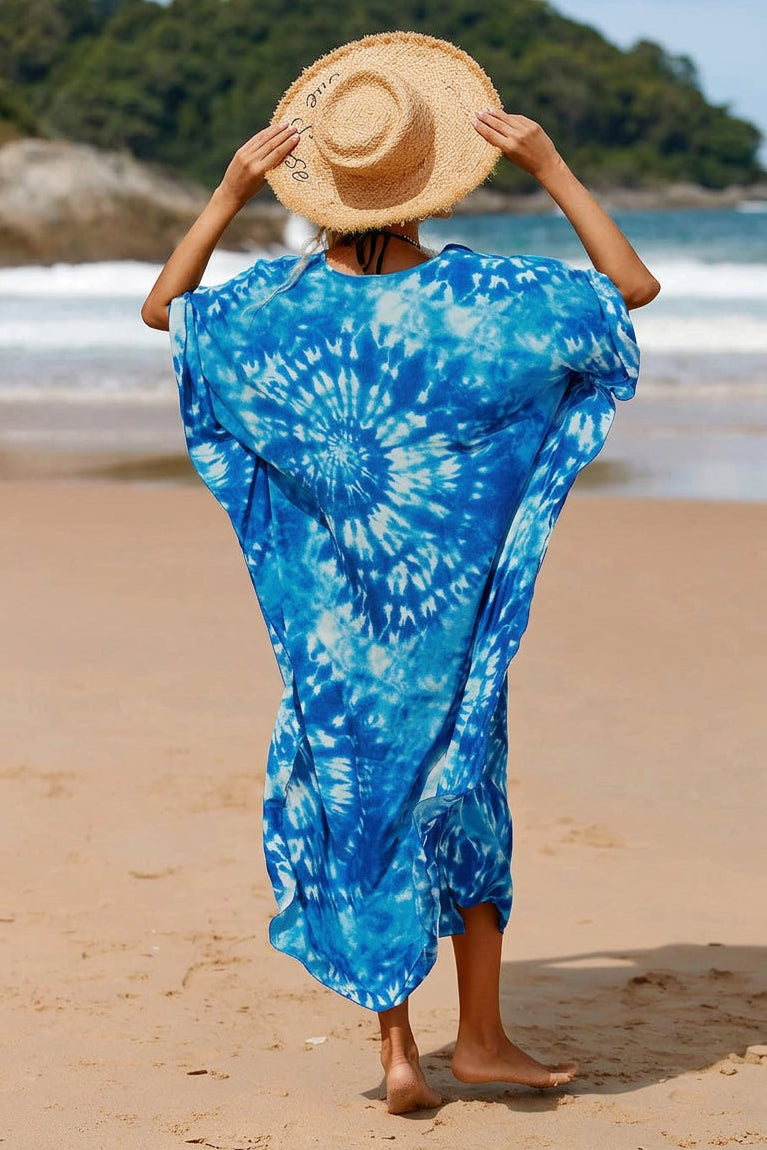 A woman wearing a loose blue and white tie-dye kaftan dress and a straw sun hat.