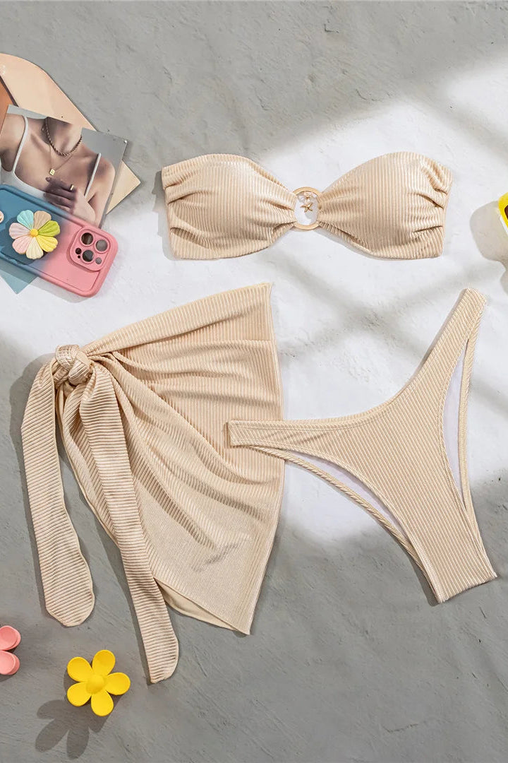 Beige bikini set with cover up on a gray surface 
