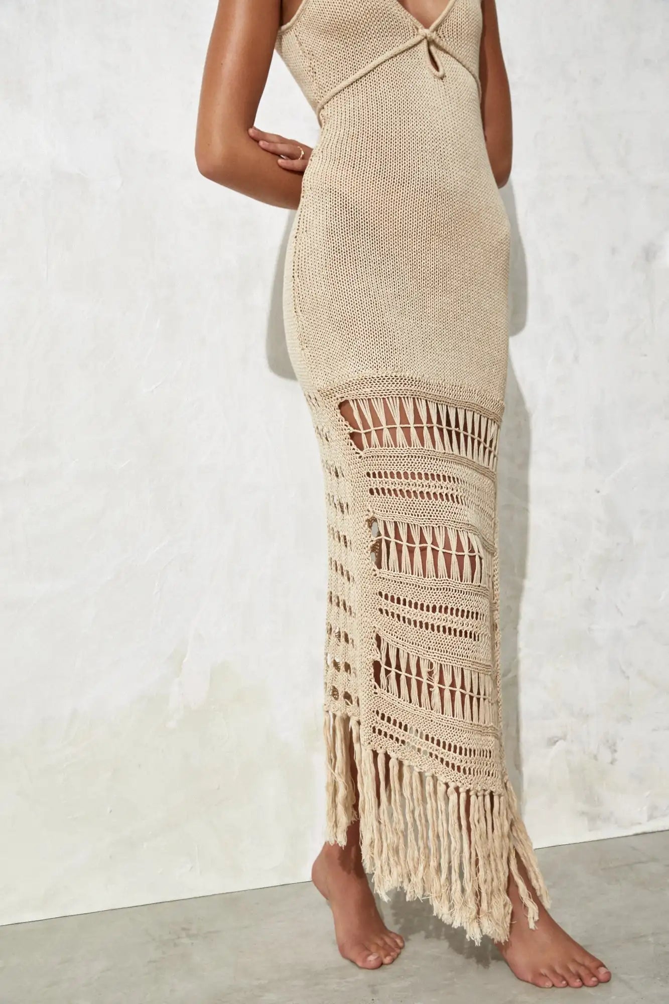 Beige knit dress with fringe details on a white background