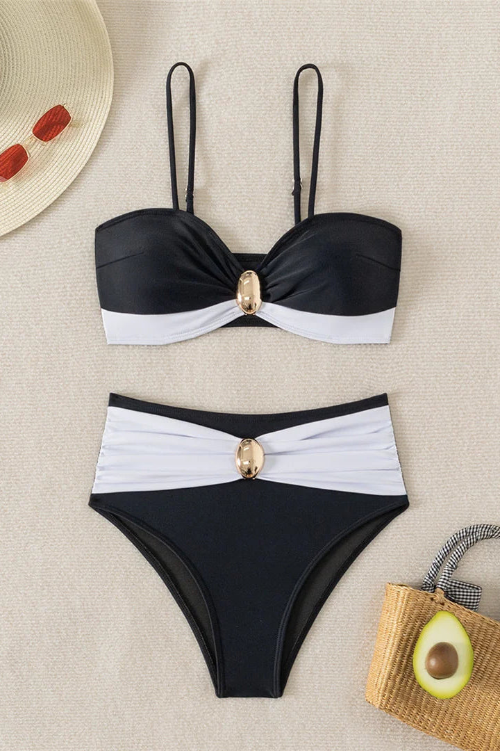 Black and white bikini set with decorative elements on a beige surface.