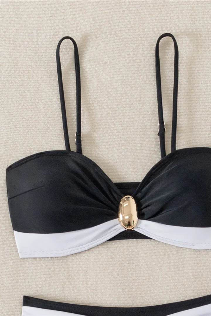 Black and white bikini top with a gold accent on a beige background