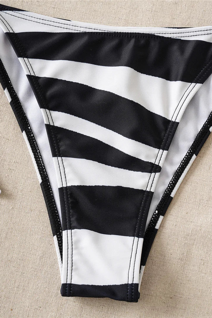 Black and white striped bikini bottom on a beige fabric background