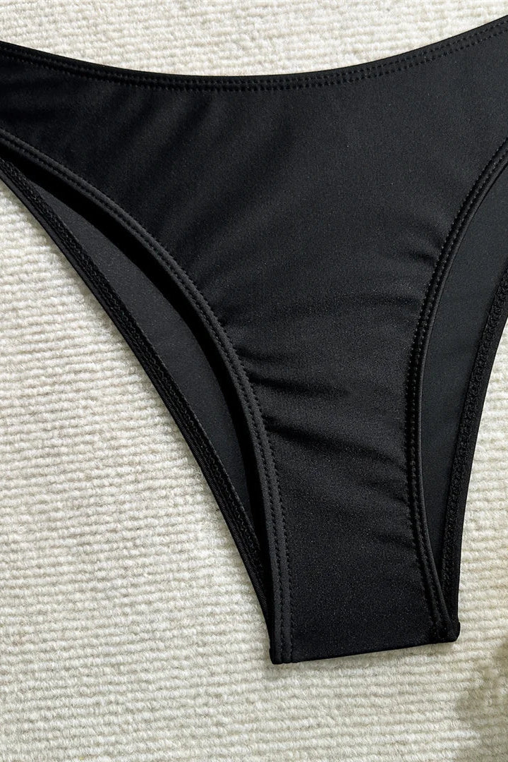 Black bikini bottom on a textured surface with flowers