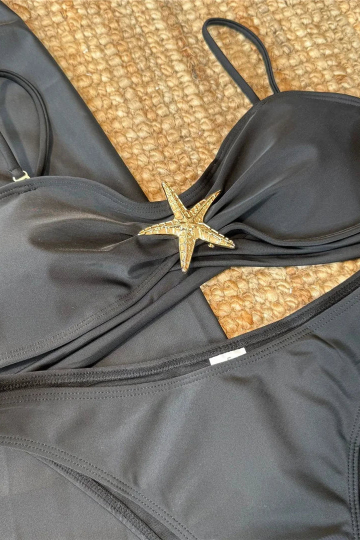 Black bikini set with a starfish accessory on a textured surface