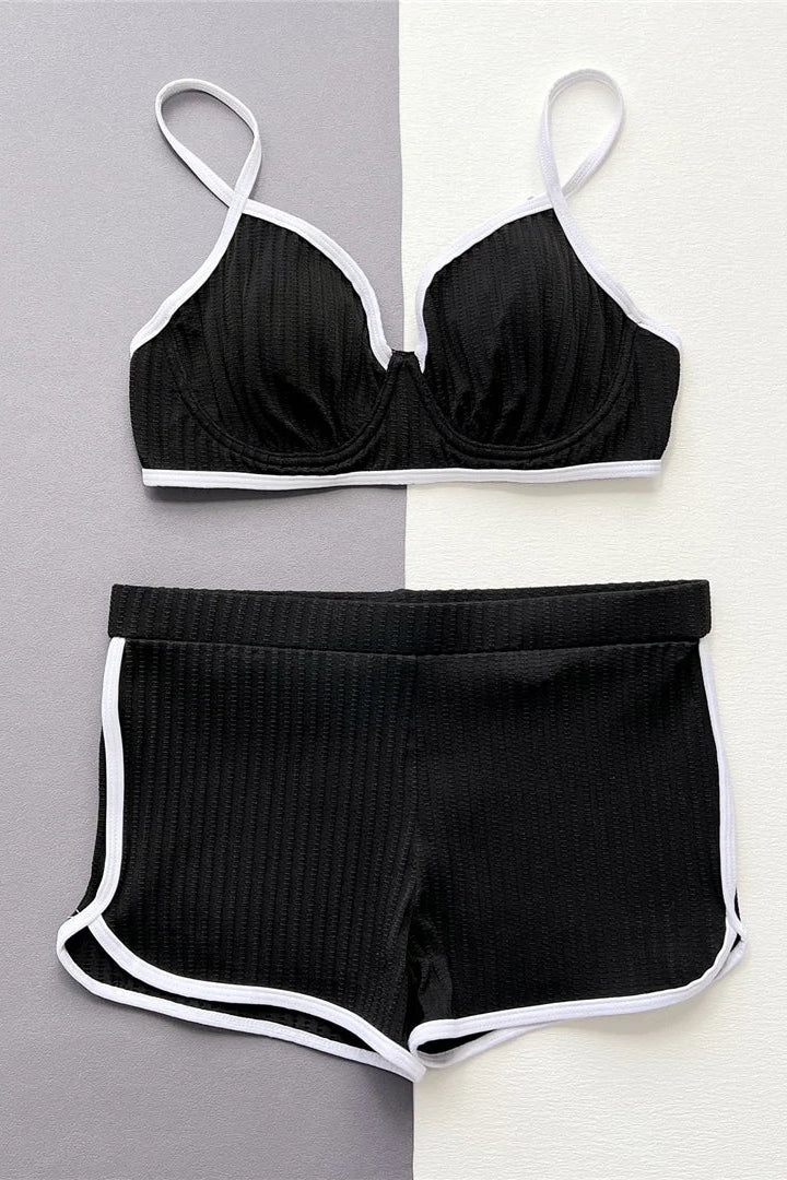 Black bikini set with white trim on a gray and white background