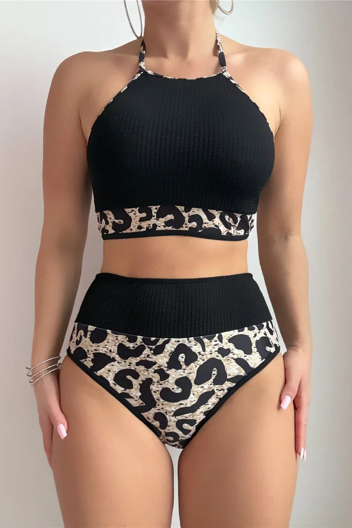 Black bikini top and high-waisted bottoms with leopard print details on a plain background