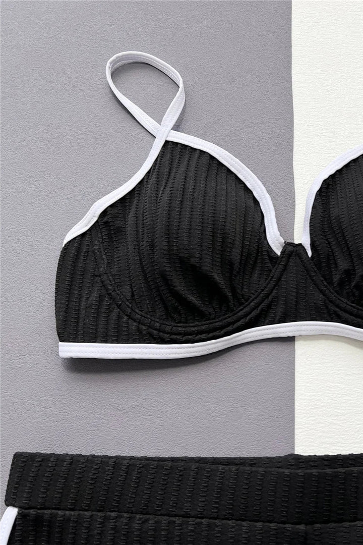 Black bikini top with white trim on a gray and white checkered background