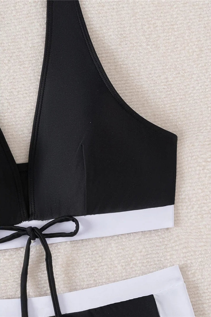 Black bikini top with white trim on a textured beige background