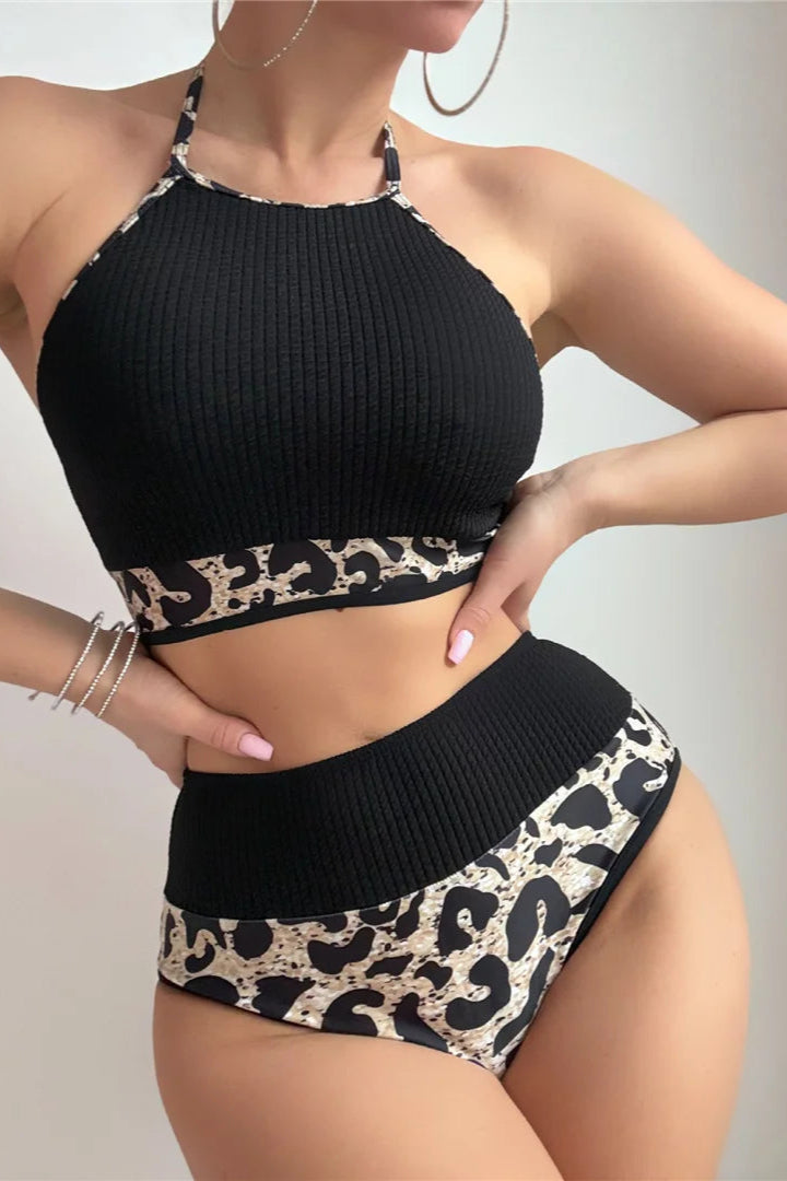 Black ribbed bikini top and leopard print shorts on a plain background