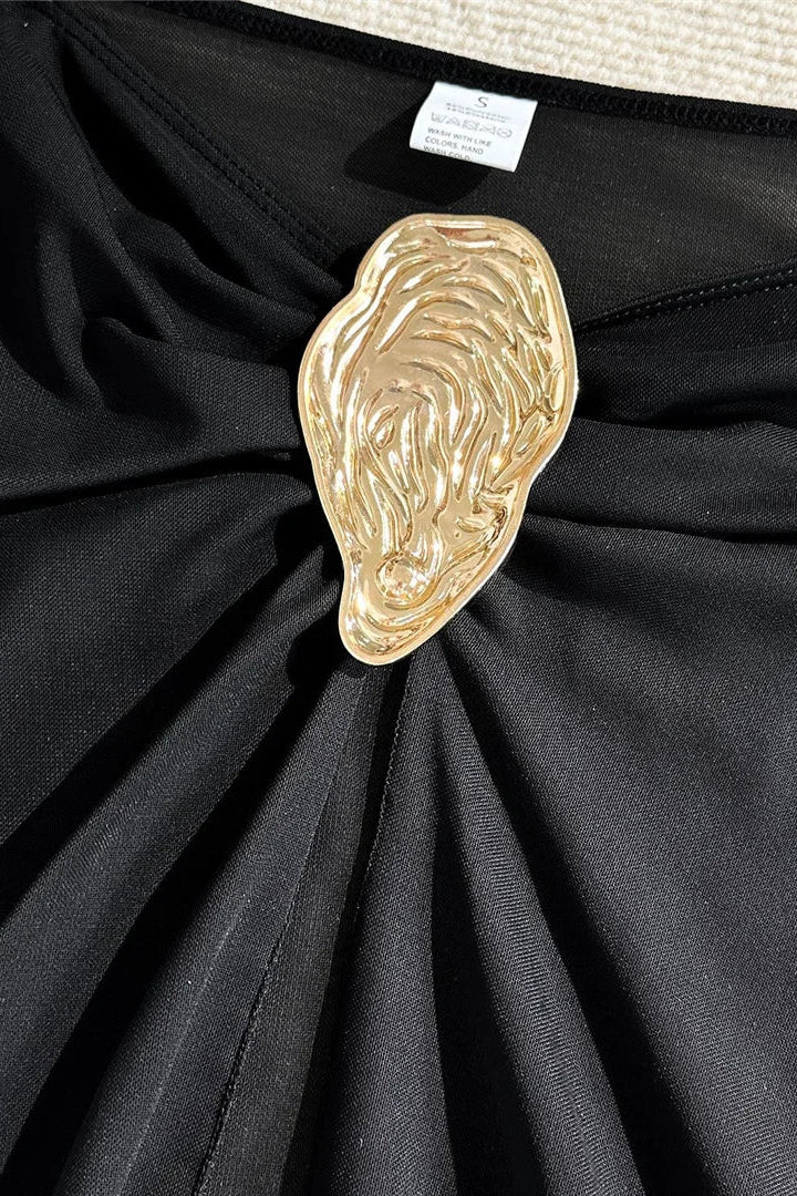 Black sarong with a gold decorative element on a textured surface