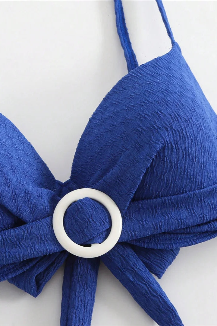 Blue bikini top with a white ring detail on a white background