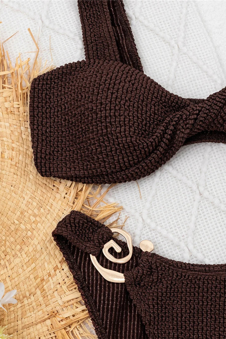 Brown bikini set on a white towel with straw mat background