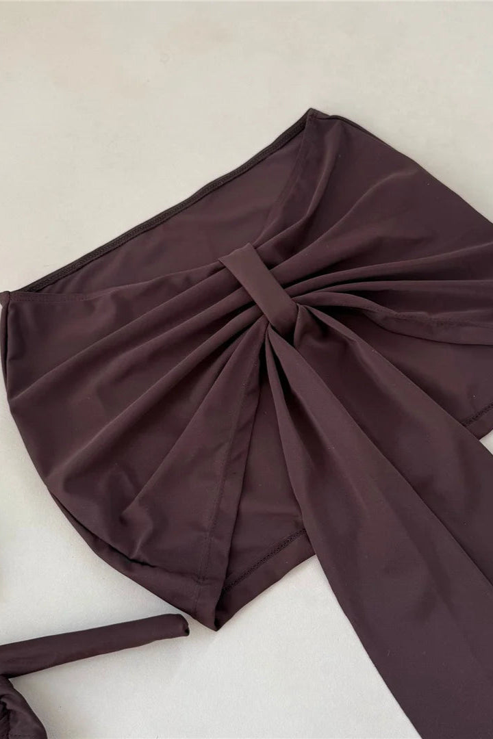 Brown bikini set with a large bow on a light beige background