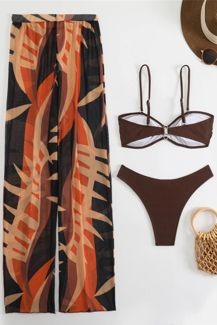 Brown bikini set with matching cover up pants, hat, sunglasses, and bag on a white background