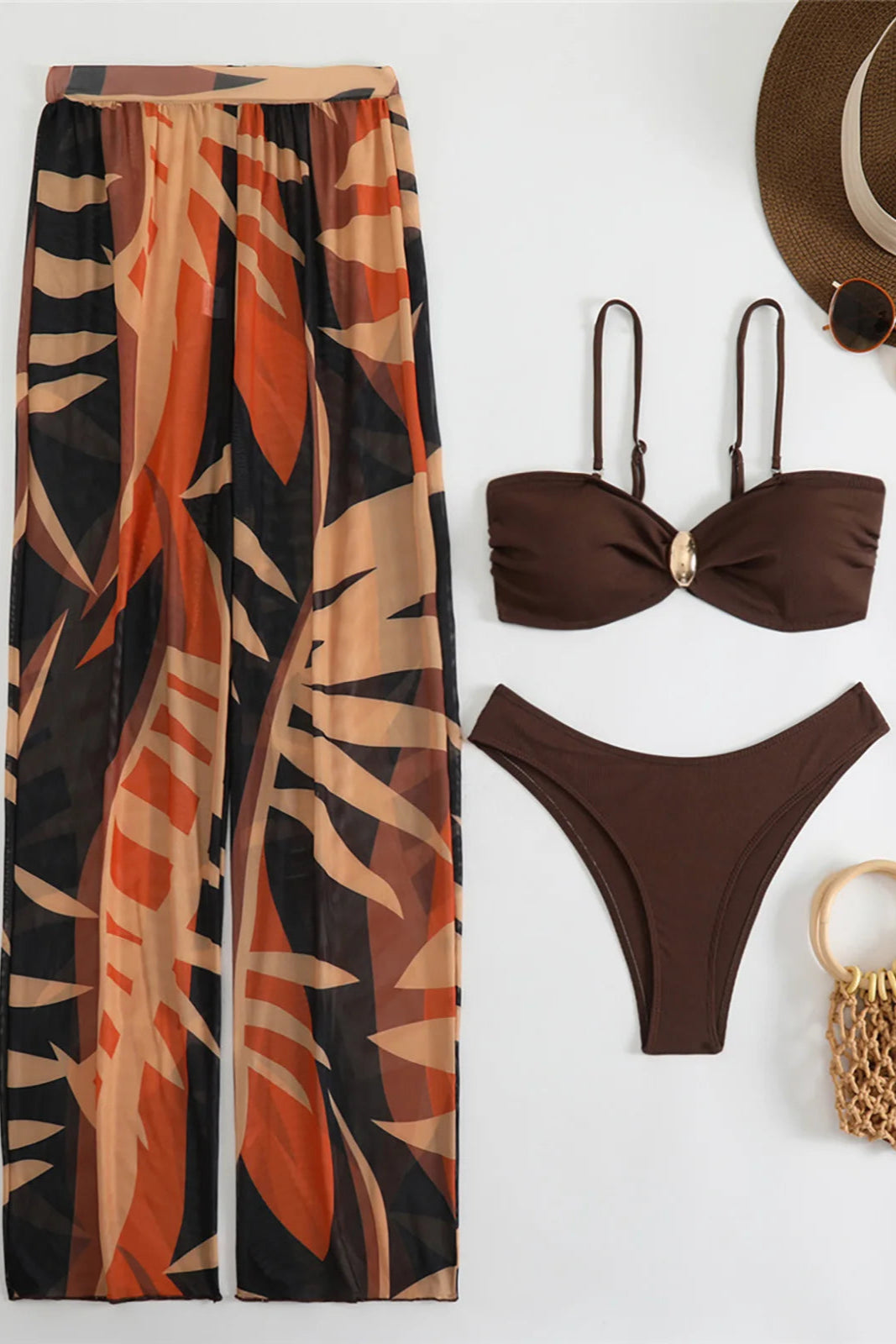 Brown bikini set with matching long pants, hat, sunglasses, and bag on a white background
