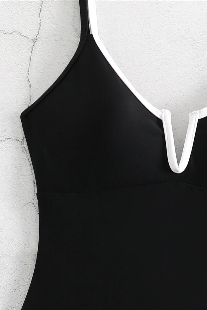 Close-up of a black sleeveless top or dress with thin straps and a white V-shaped trim at the neckline