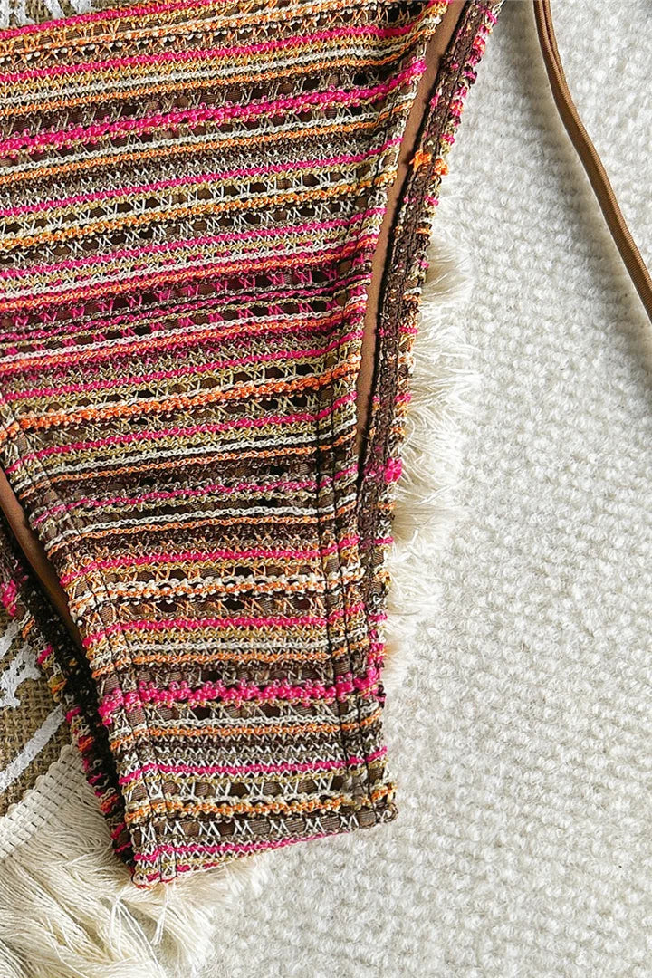 Close-up of a colorful striped bikini  bottom with fringes on a textured surface