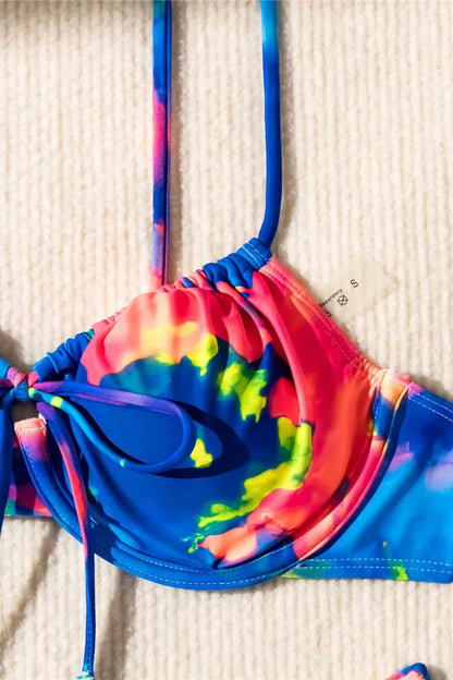 Colorful tie-dye bikini set on a beige textured surface