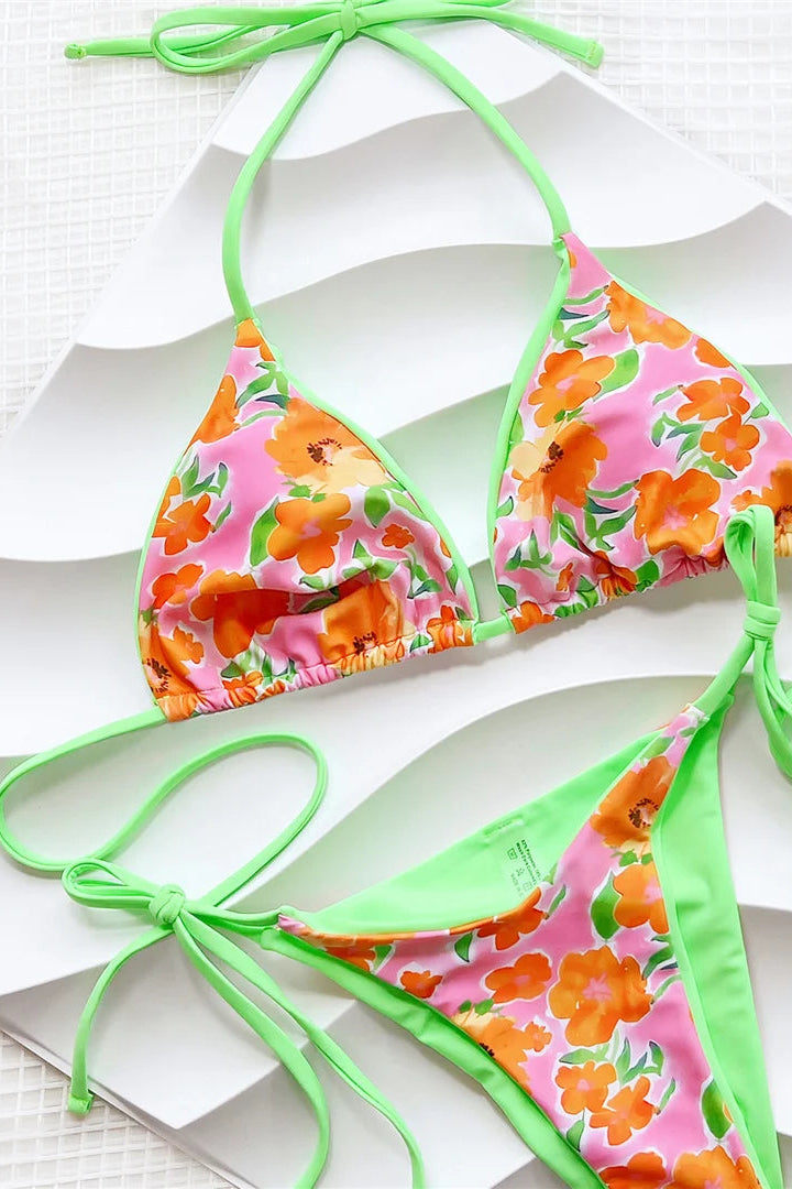 Floral halter neck lace up bikini set with green straps on a white background
