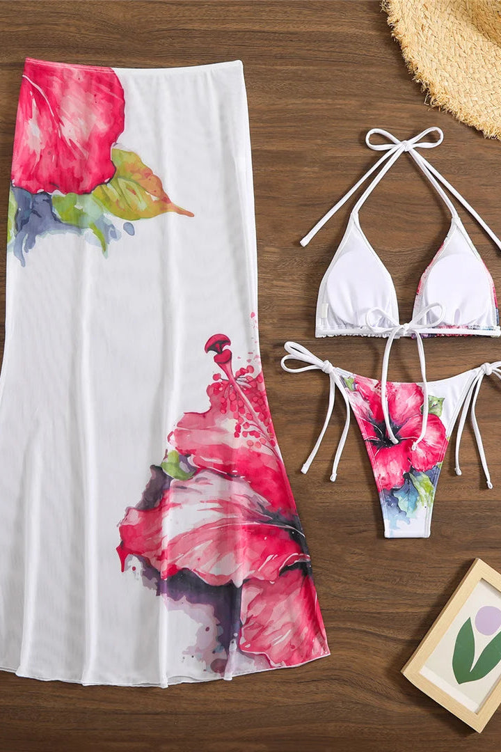 Floral sheer skirt and bikini set on a wooden surface with a small framed picture.