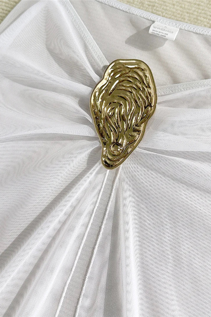 Gold brooch on a white cover up skirt 