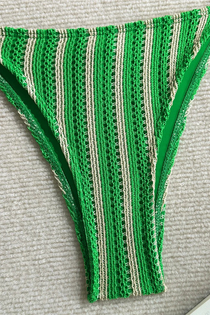Green and white striped bikini bottom on a textured surface