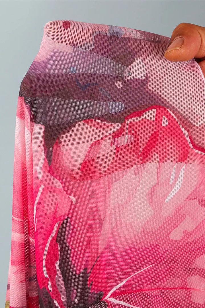 Hand holding a pink floral mesh skirt against a gray background