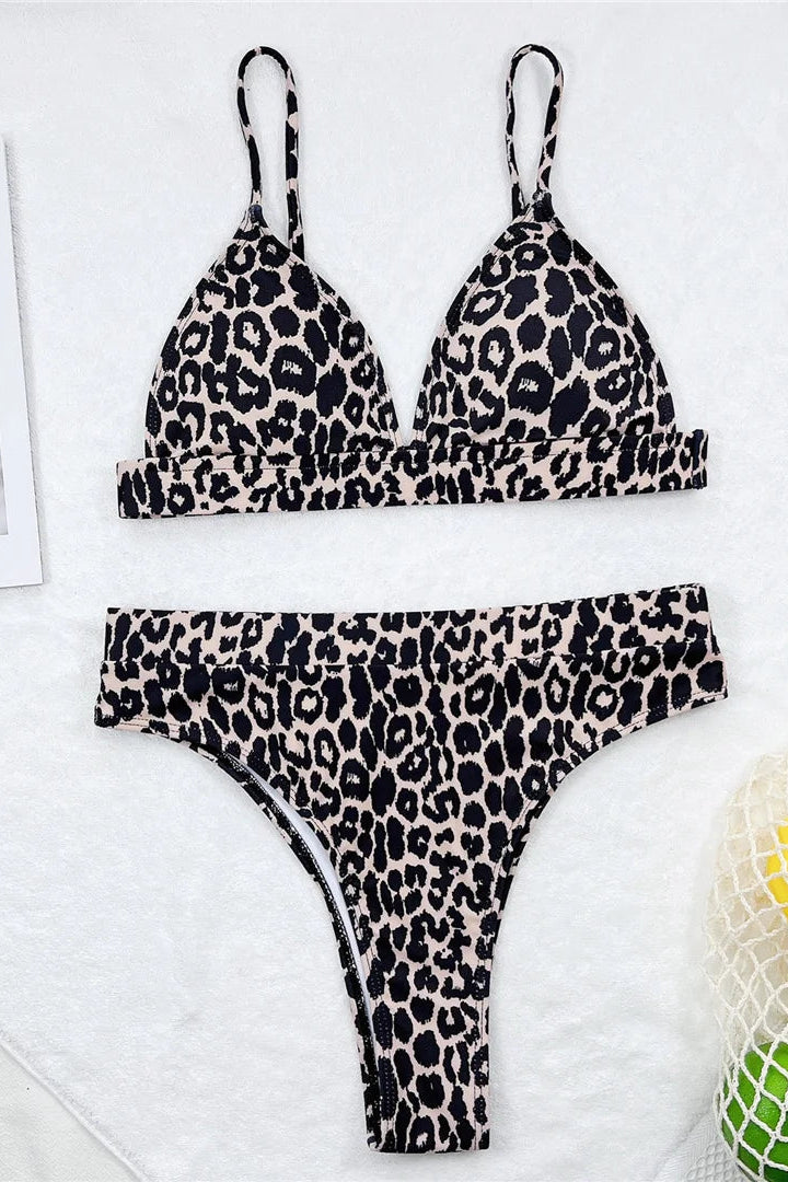 Leopard print bikini set on a white surface with a newspaper and yellow object in the background.