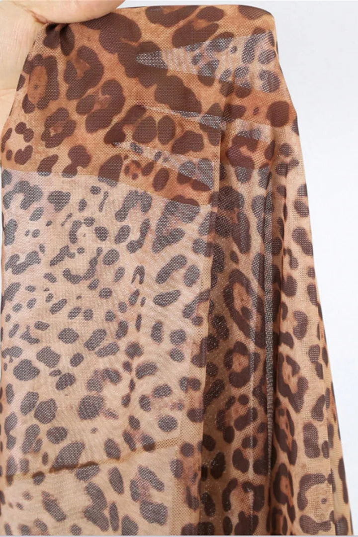 Leopard print cover up skirt fabric held by a hand on a white background