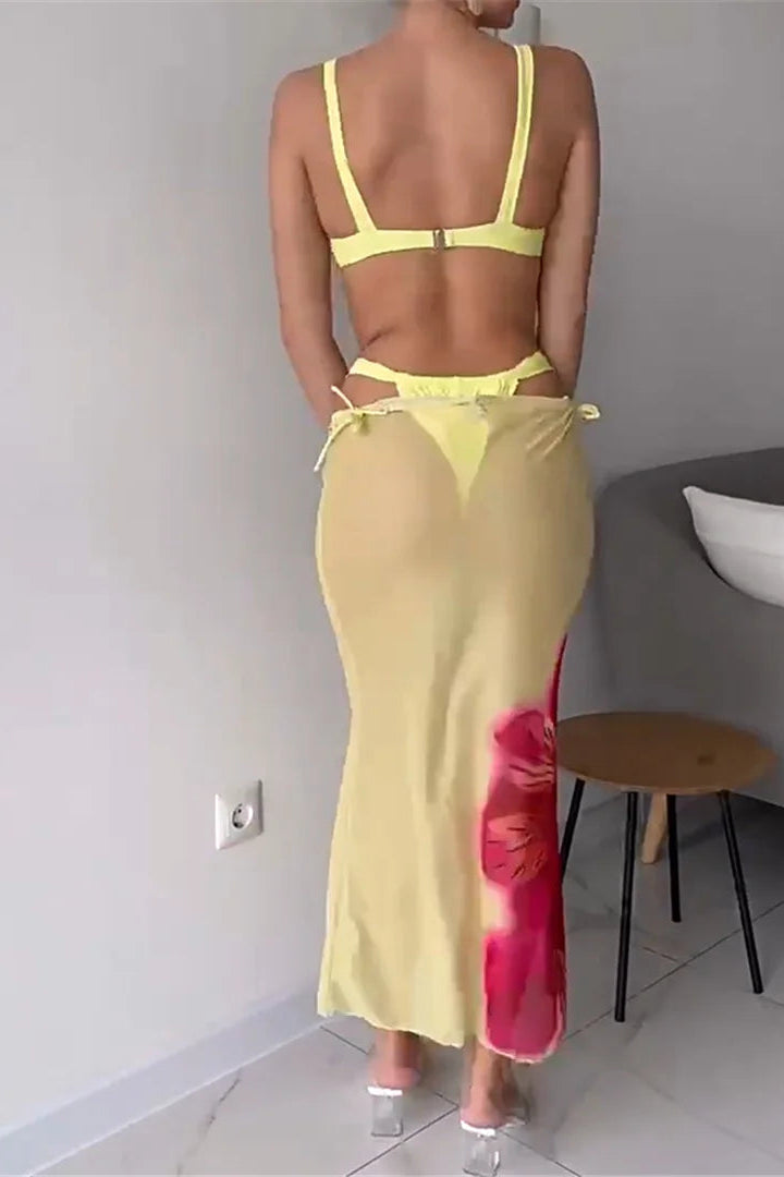 Person wearing a yellow bikini and long skirt with pink floral design in a room.