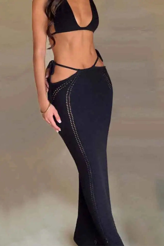 Person wearing black strappy top and high-waisted skirt on a plain background