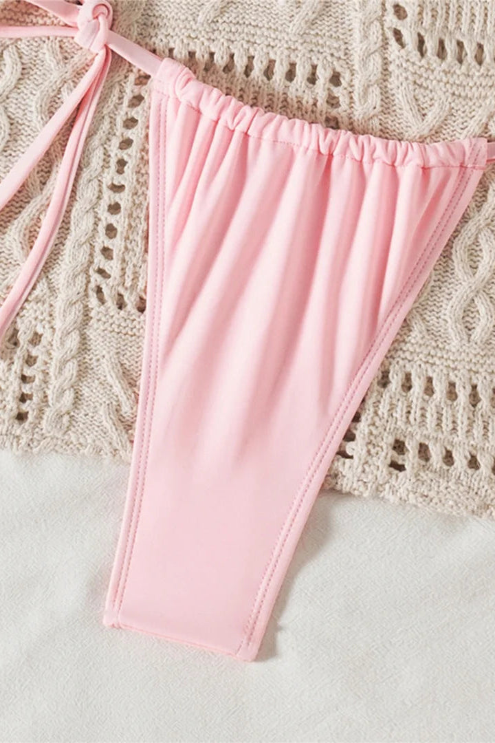 Pink bikini bottom on a textured beige surface