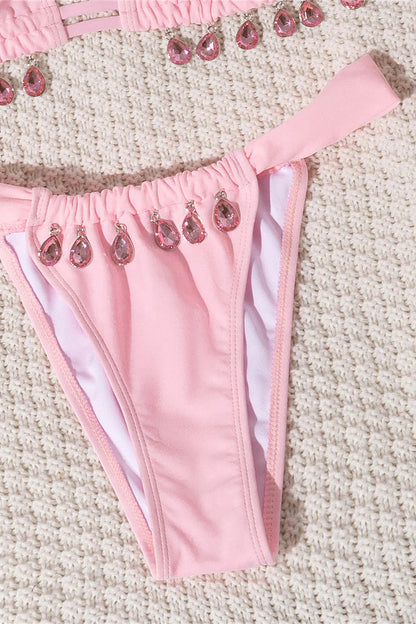 Pink bikini bottom with embellishments on a textured surface