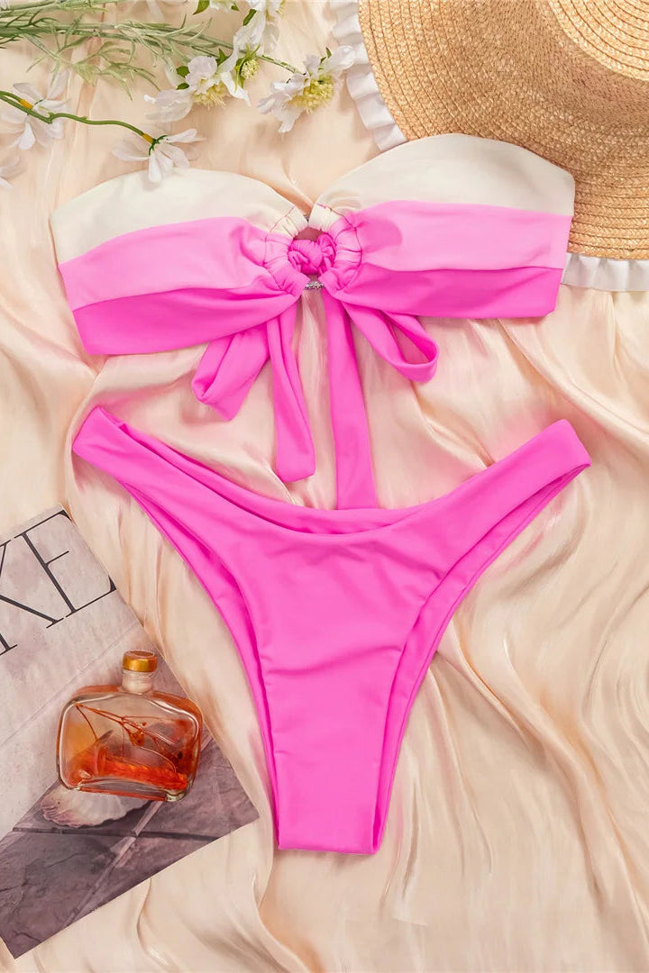 Pink bikini set with a straw hat and flowers on a light fabric background