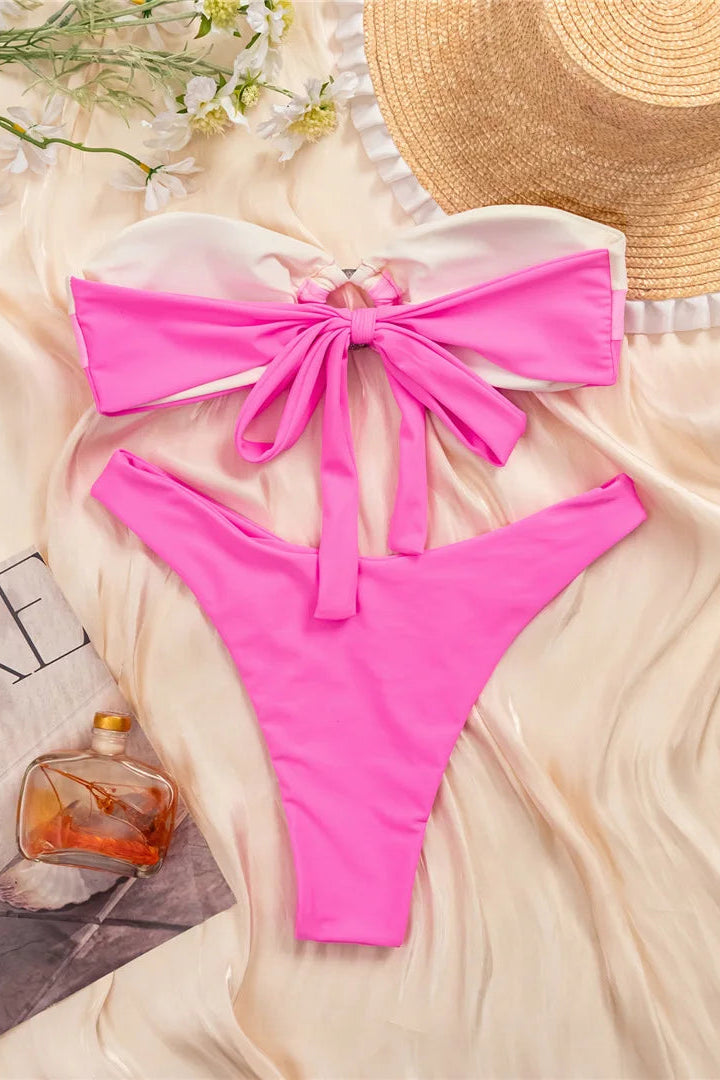 Pink bikini set with a straw hat on a light fabric background