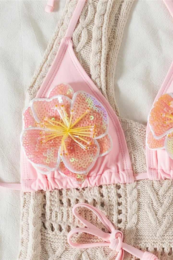 Pink bikini top with 3D floral design on a textured surface